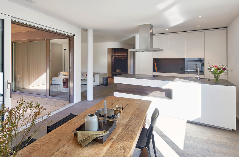 Helle Wohnküche mit Kochinsel und Essbereich, raumhohe Schiebetüren zur Terrasse – Neubauwohnung in Beromünster.