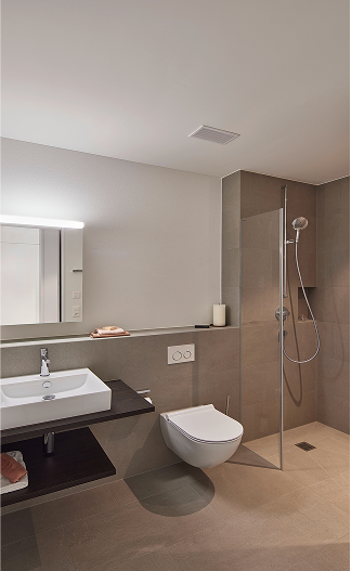 Modernes Bad mit Waschtisch, WC und bodengleicher Walk-in-Dusche in Feinsteinzeug.
